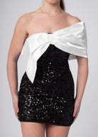 Korte zwarte sequin bandeau off shoulder jurk met grote witte satijnen strik, voor chique feesten.